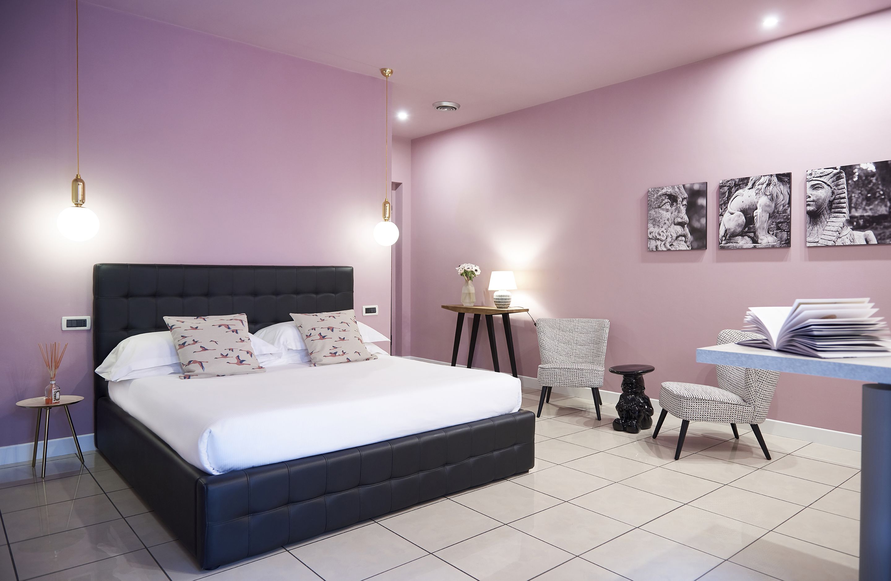 A modern bedroom with a large bed, bedside tables, a desk, and wall art.