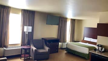 Habitación de hotel con cama, escritorio, silla, lámpara, televisor y calefactor.