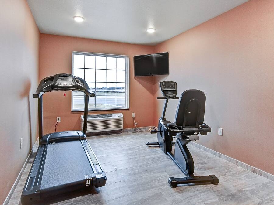 A gym with a treadmill, elliptical, and stationary bike, a window with a view, and a mounted TV.