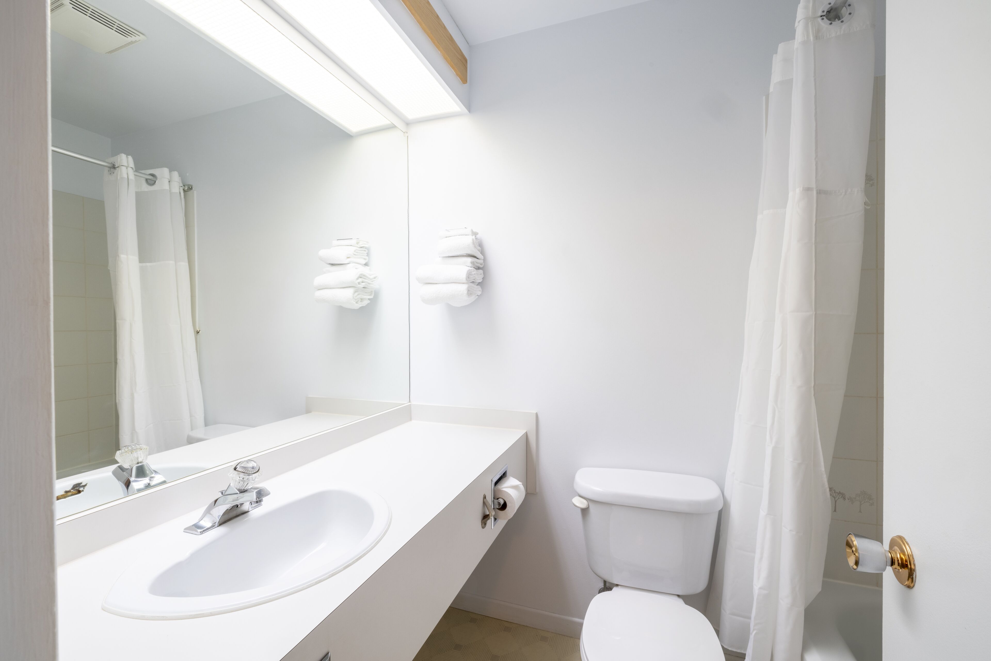 Ein modernes Badezimmer mit Waschbecken, Spiegel und Toilette in Weiß.