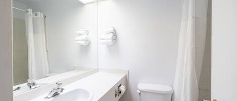 A modern bathroom with a white sink, mirror, and toilet.