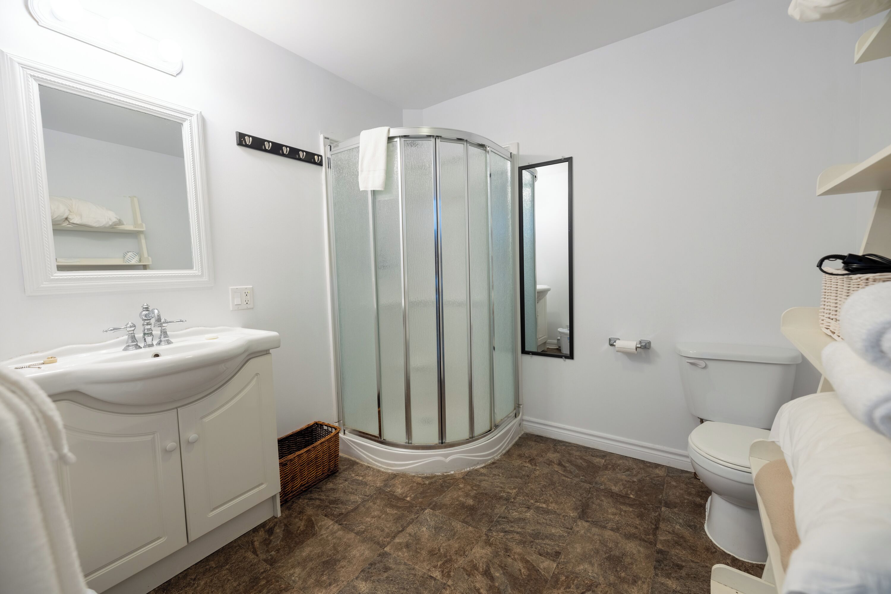 Un baño con un lavabo blanco, cabina de ducha con mampara de vidrio y un inodoro.