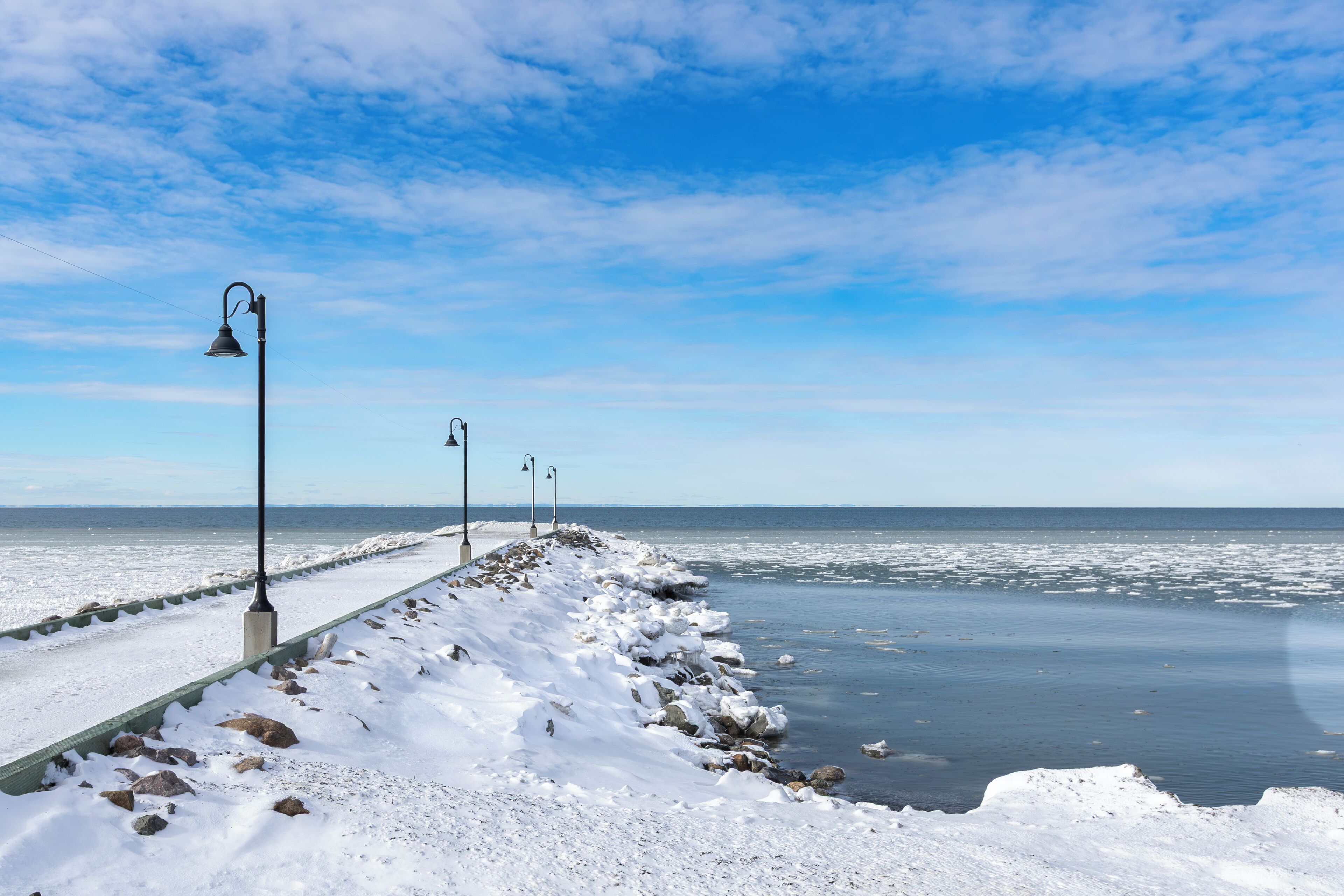 Un muelle cubierto de nieve con faroles que se adentran en el agua.