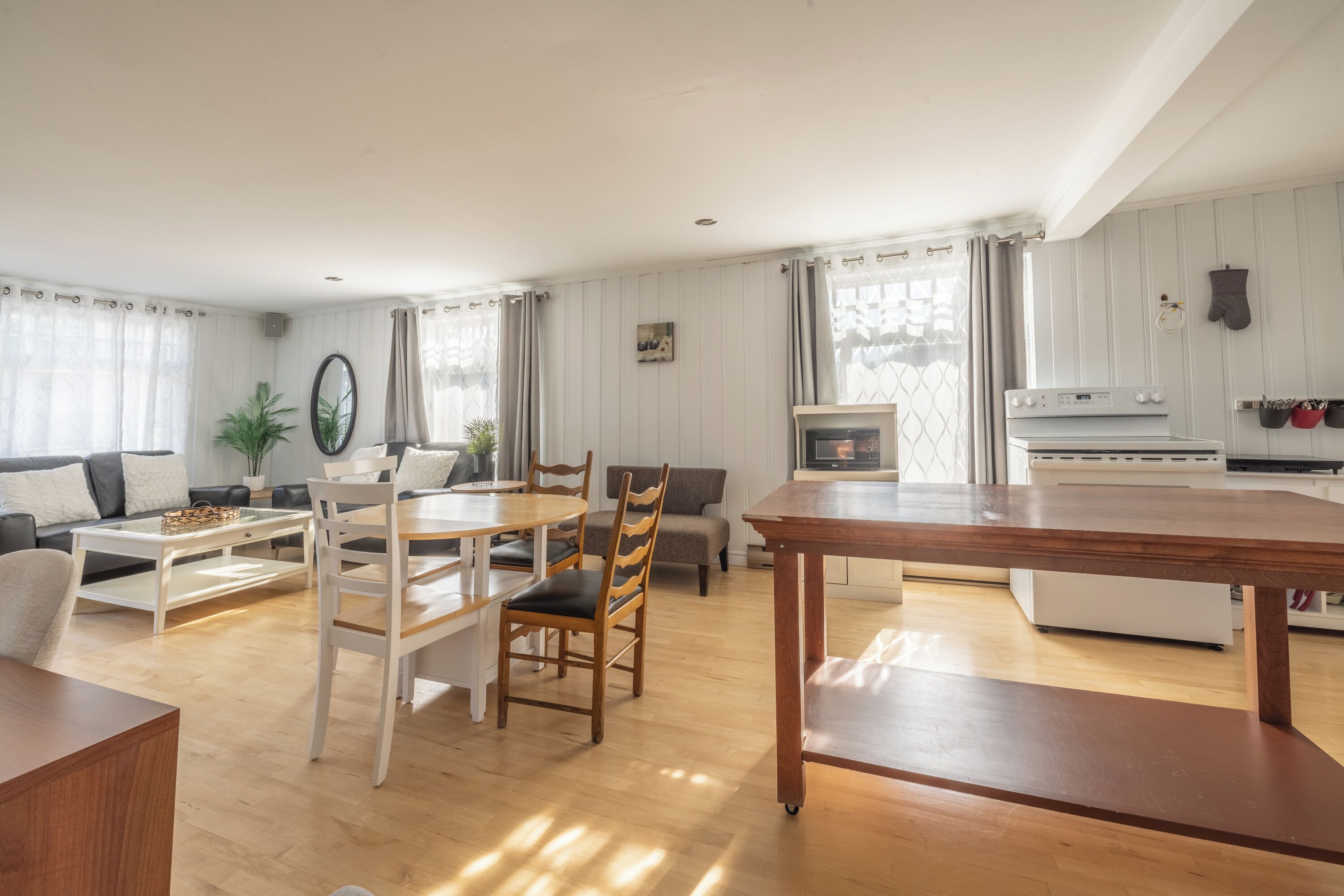 Amplia sala de estar con mesa de comedor, sillas, sofá y área de cocina con estufa y horno.
