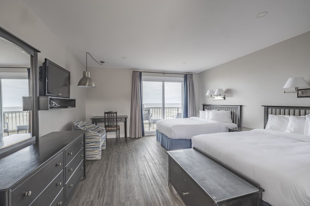 Ein Hotelzimmer mit zwei Betten, einem Schreibtisch, einem Stuhl, einem Fernseher und einem Balkon mit Blick.
