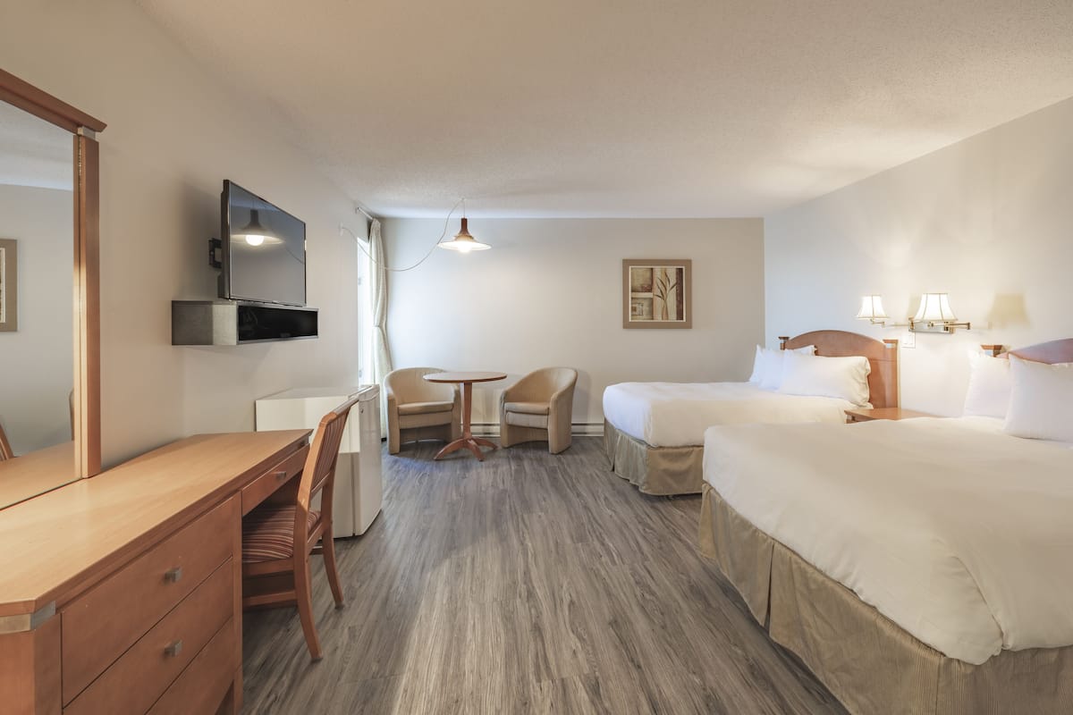 Ein Hotelzimmer mit Schreibtisch, zwei Stühlen, einem Bett, einem Fernseher und einem kleinen Tisch.