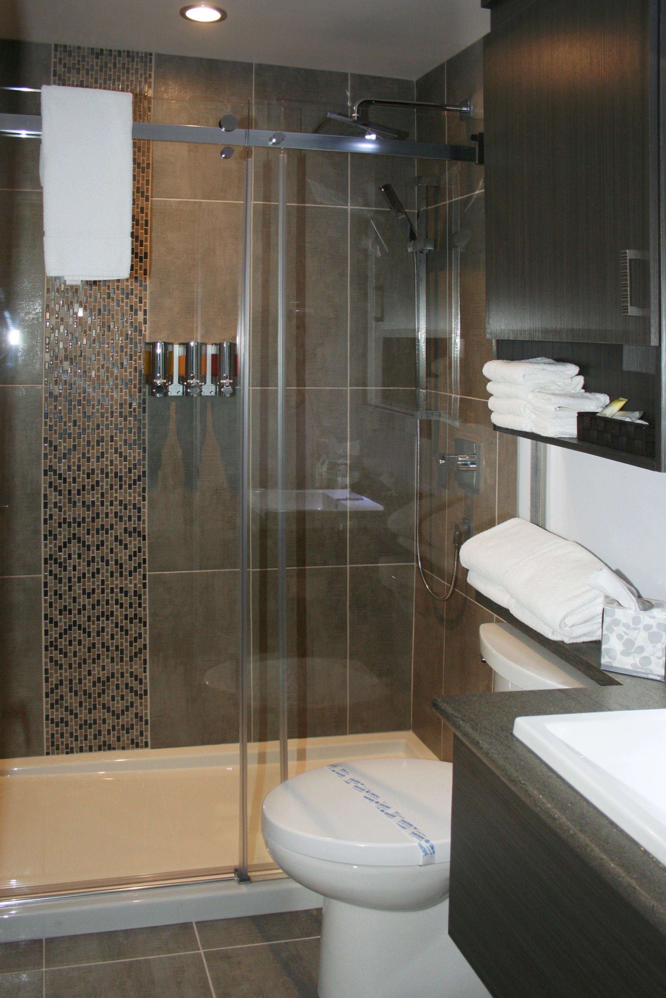 Een moderne badkamer met een douchecabine van glas, een toilet en een wastafel met spiegel erboven.