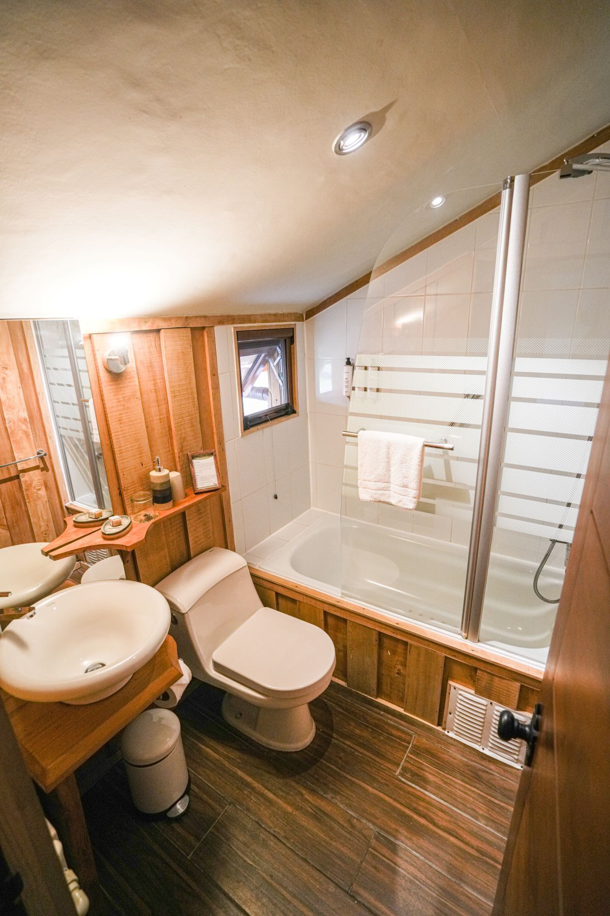 Un baño pequeño con tocador de madera, inodoro, bañera y cabina de ducha.