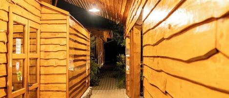 Un pasillo de madera con suelo de baldosas, paredes de madera y una puerta a la izquierda.