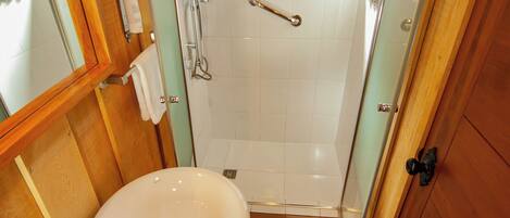 A compact bathroom with a wooden vanity, a sink, and a shower enclosure.