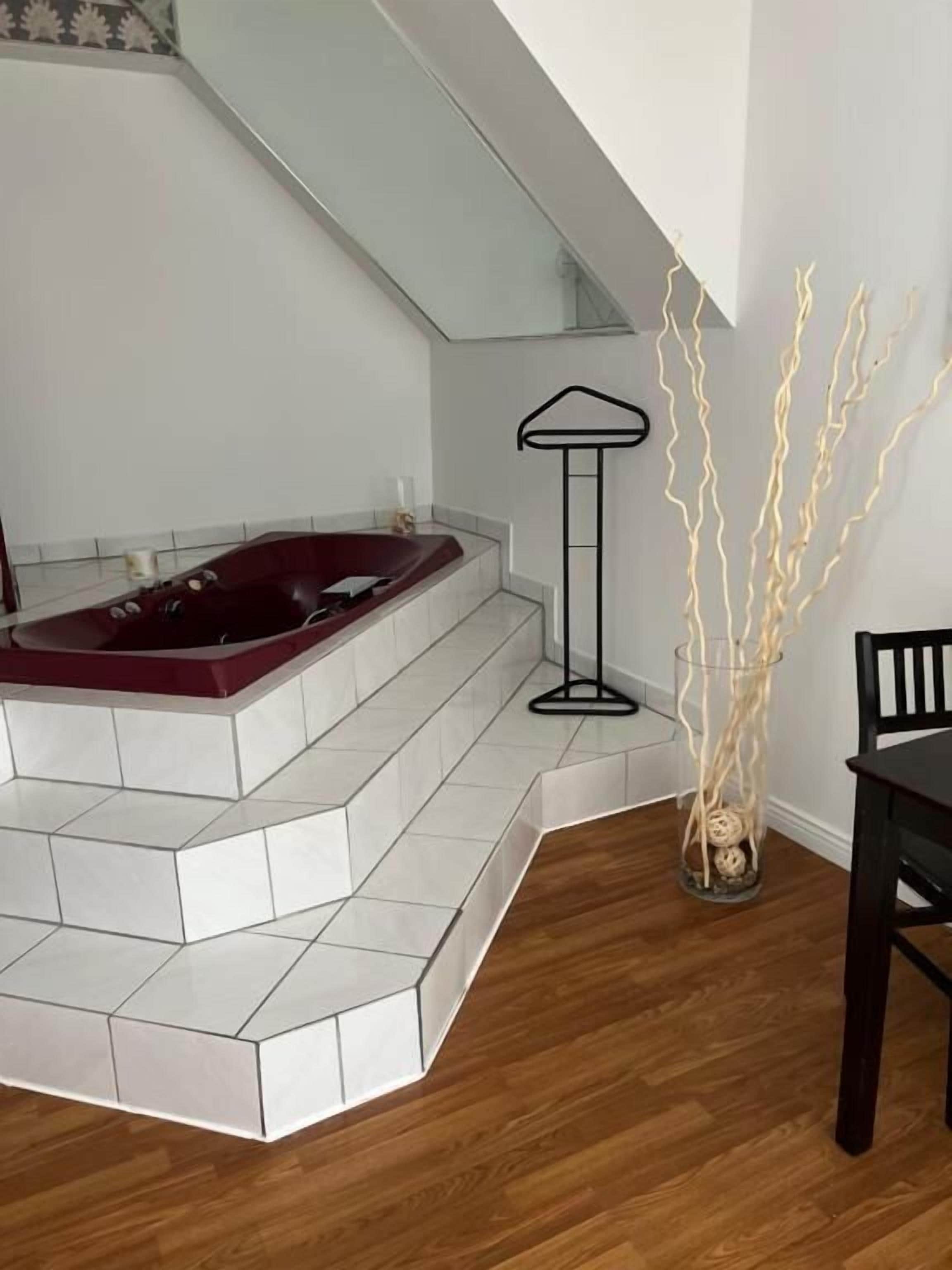 Een badkamer met een bad, een stoel en een decoratieve vaas.