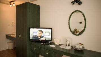 Ein Badezimmer mit einem dunklen Holzschrank, einem Spiegel, einem Fernseher und einer Kaffeemaschine.