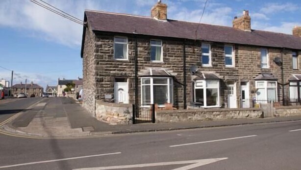 A stone building with multiple windows and a dark roof. - Haven Cottage (Seahouses)