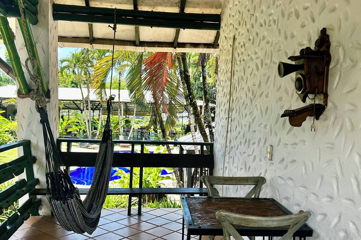 A covered patio area with a hammock, a table, and chairs.