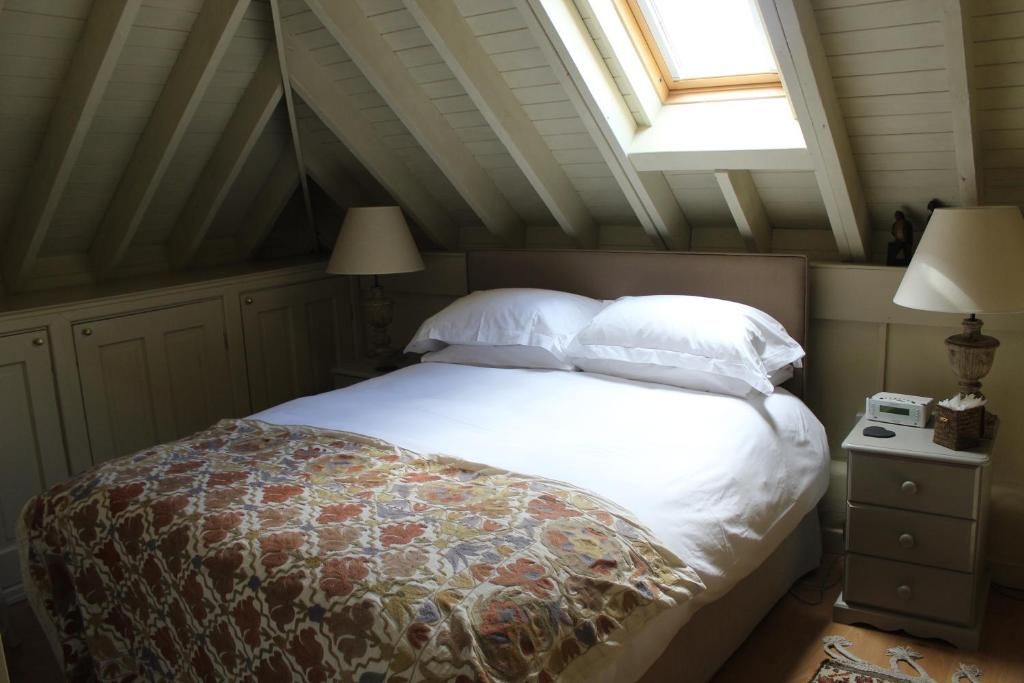 A bedroom with a bed, a nightstand, a lamp, and a skylight.