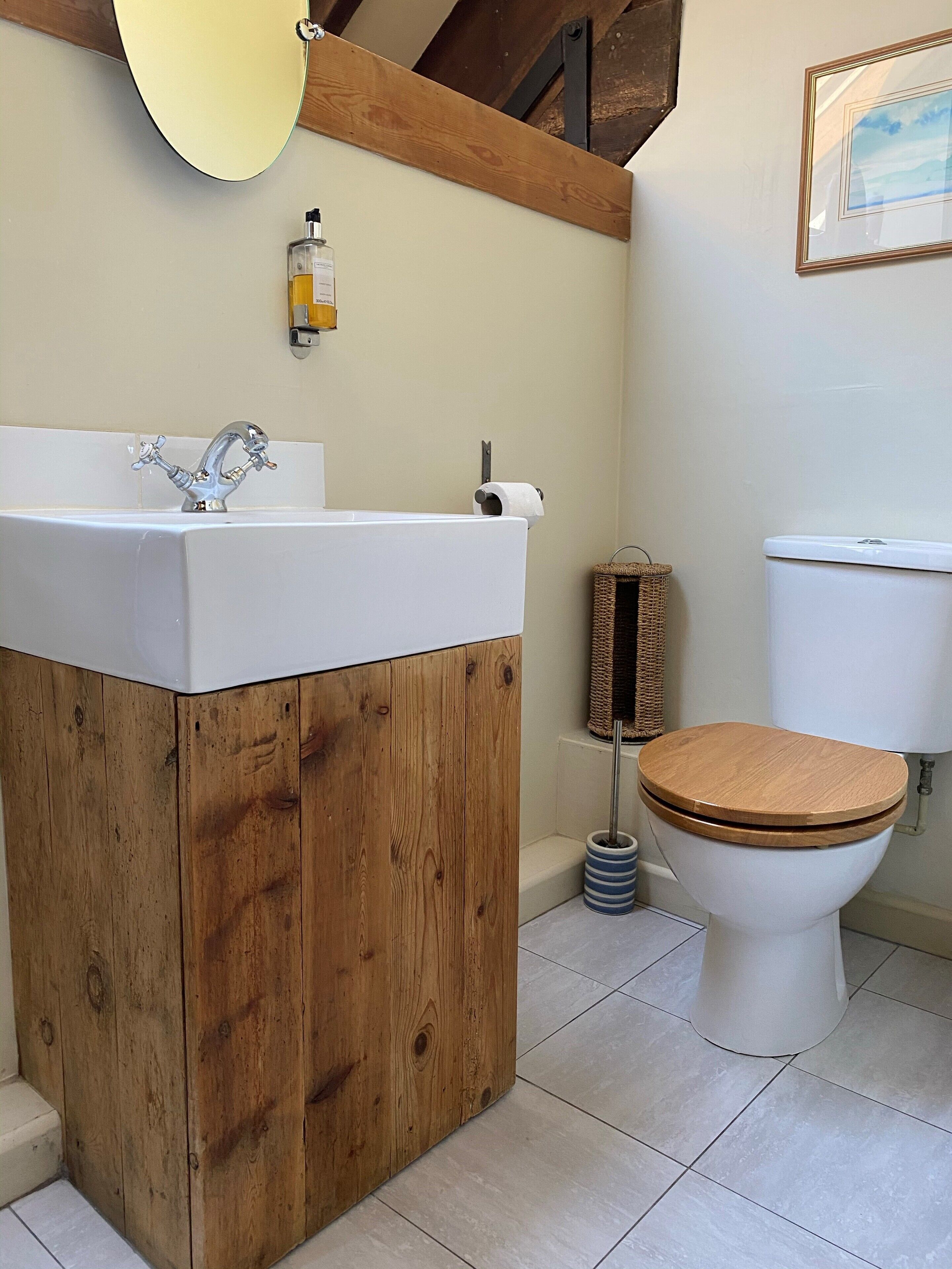Un baño con tocador de madera, un lavabo, un inodoro y un cuadro en la pared.