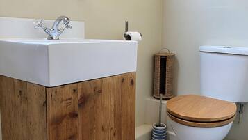 Un baño con tocador de madera, un lavabo, un inodoro y un cuadro en la pared.