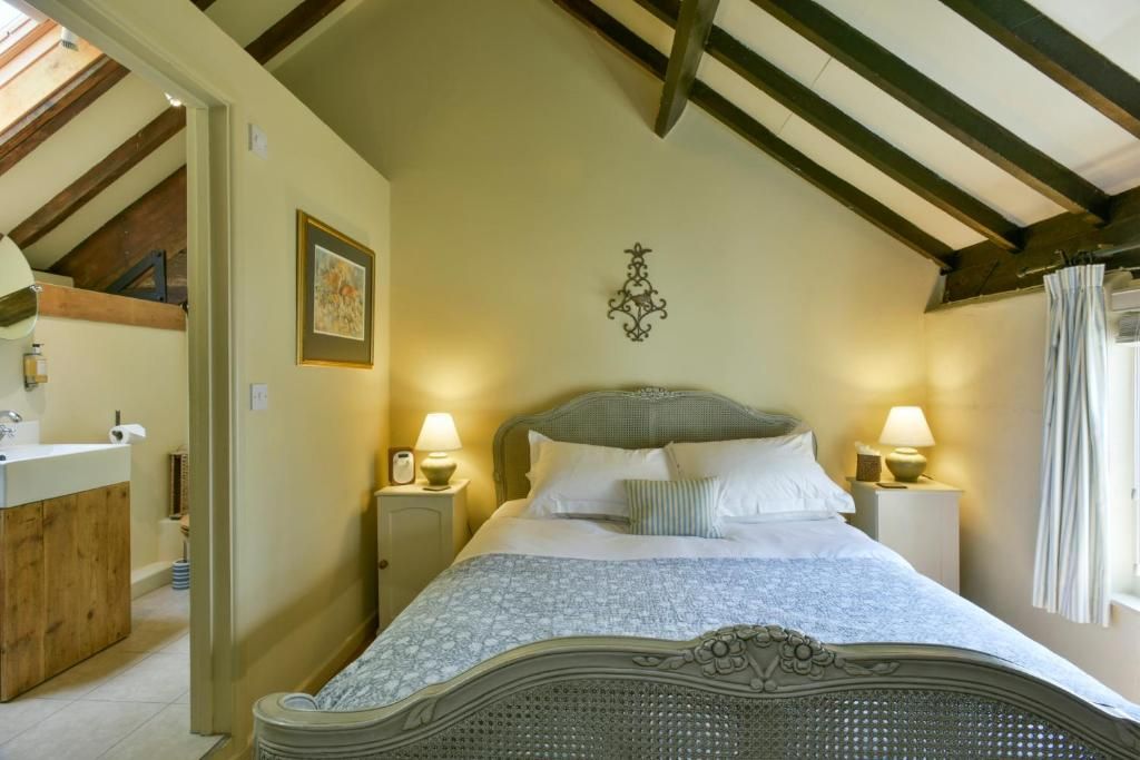 A bedroom with a bed, bedside lamps, a picture on the wall, and a window with curtains.