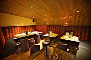 A restaurant interior with wooden ceiling, red and black patterned walls, and multiple dining tables with chairs. - St Ola Hotel (Kirkwall)