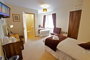 A hotel room with a bed, a desk, a chair, a television, and a bathroom visible through an open door. - St Ola Hotel (Kirkwall)