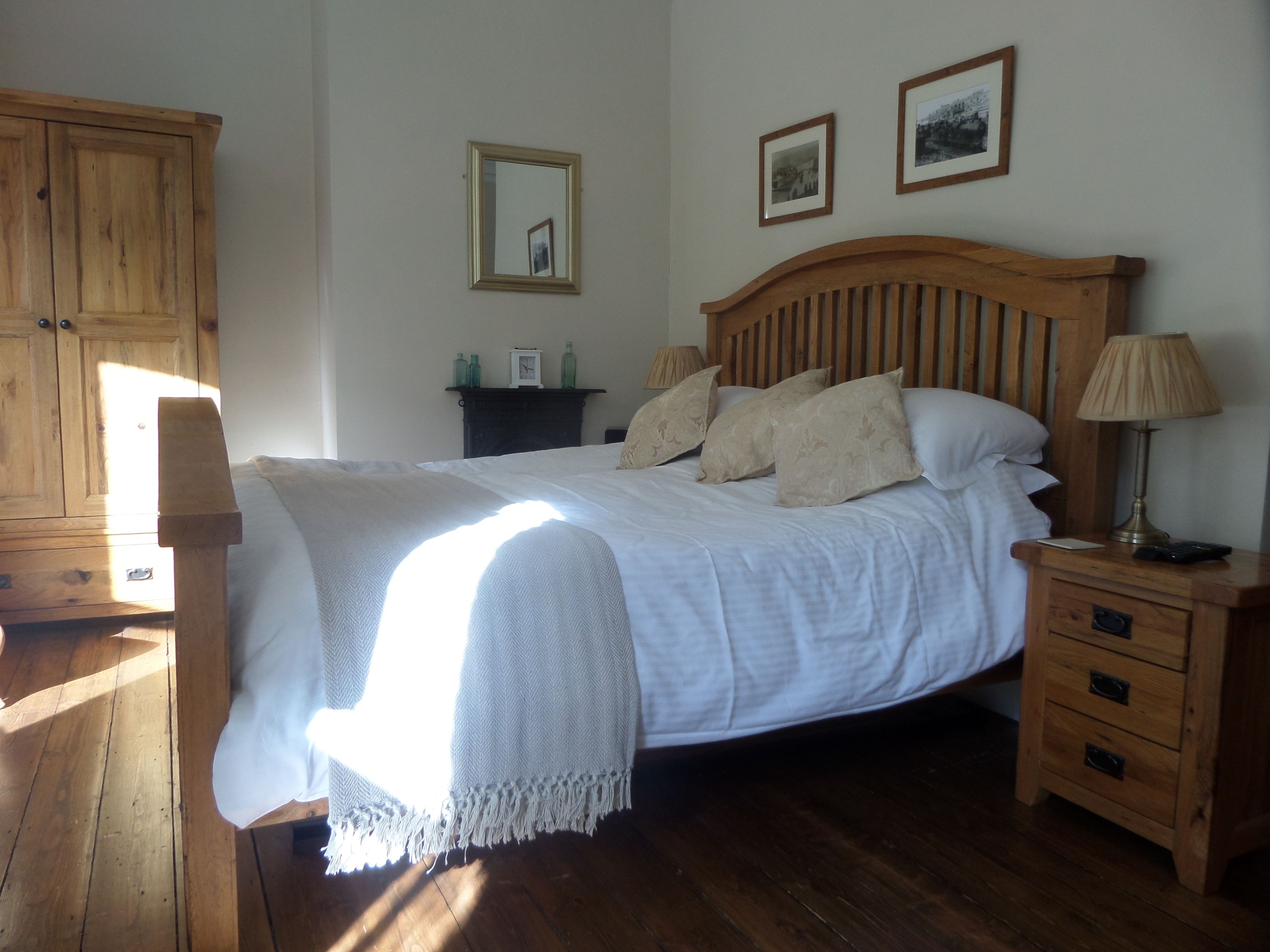 Une chambre à coucher avec un lit en bois, des tables de chevet, une commode, une lampe et une armoire.
