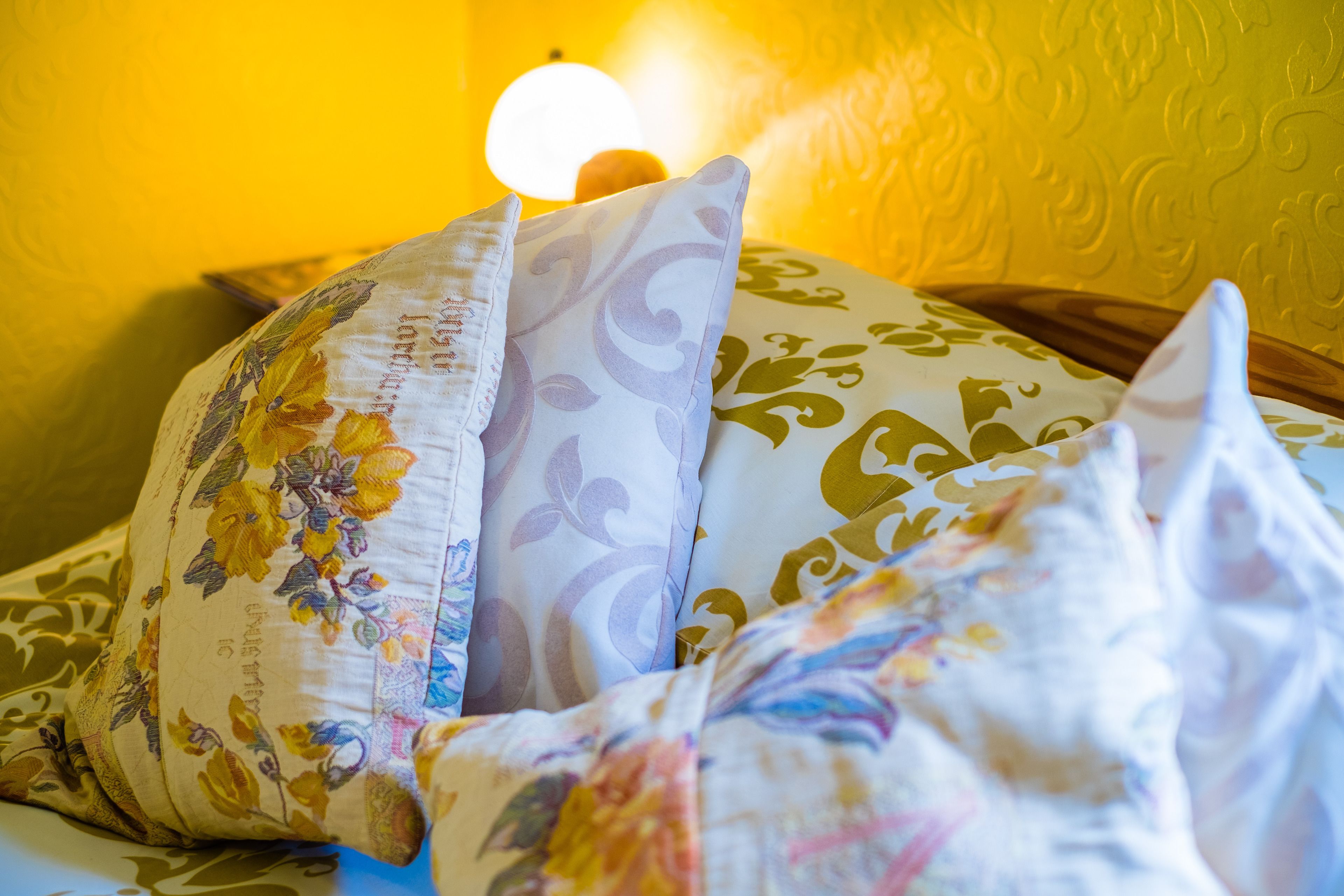 A bed with floral patterned pillows and a white comforter.