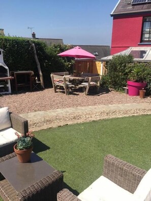 A patio with outdoor furniture, a pink umbrella, and a small garden area. - Western House B and B (Swansea)