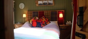 A bedroom with a bed, two bedside lamps, a clock, and a wall-mounted picture frame. - Western House B and B (Swansea)