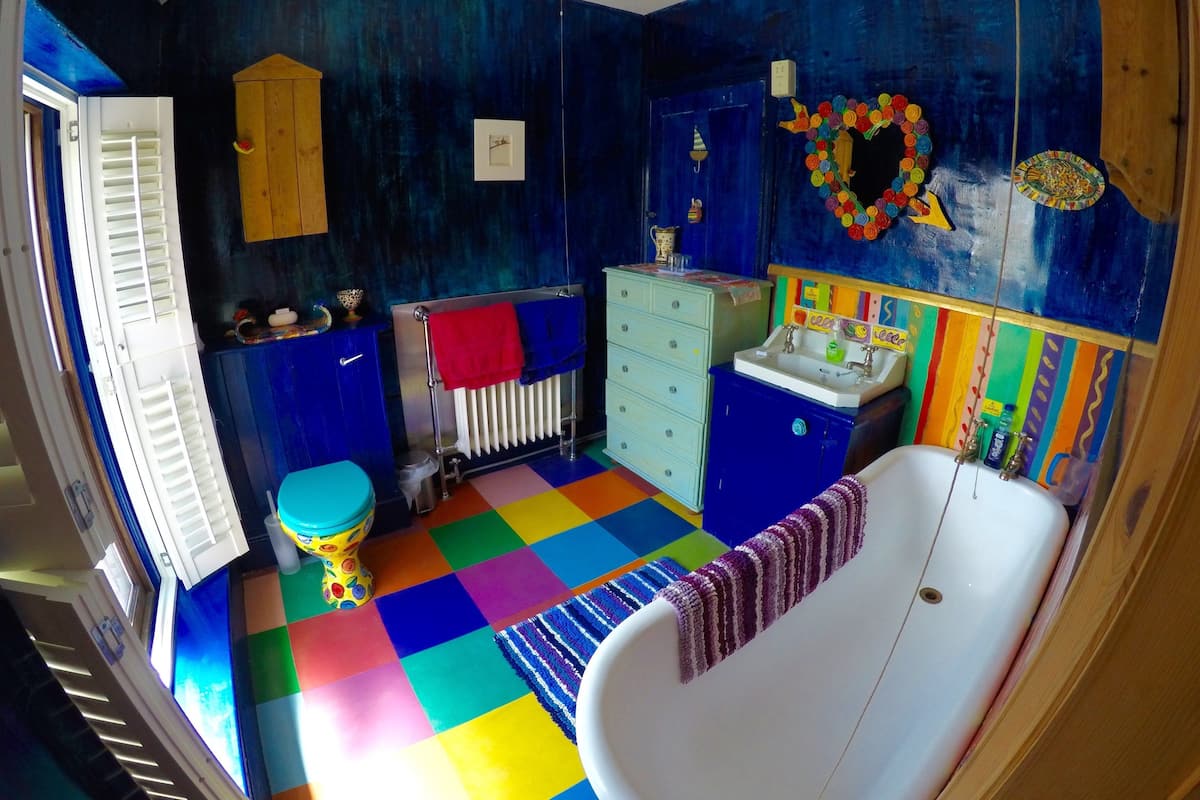 A bathroom with a colorful checkered floor, a white bathtub, a wooden cabinet, and a radiator.