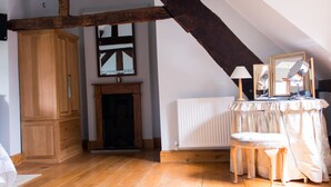 A room with wooden floors, a fireplace, a mirror, and a table with a lamp. - Huntlands Farm (Worcester)