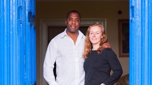 A man and a woman standing in a doorway with a blue door frame. - Huntlands Farm (Worcester)