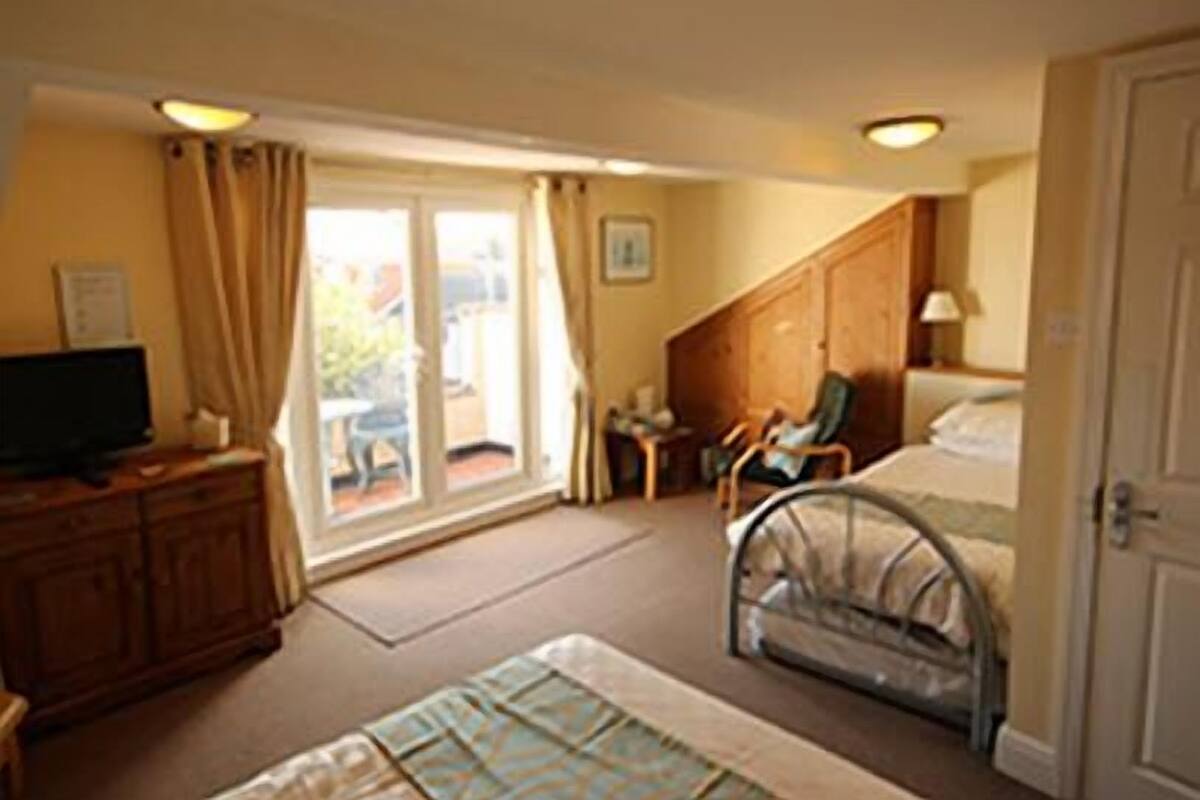 Hotelkamer met een bed, bureau, stoel, televisie en raam met gordijnen.