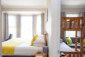 A hotel room with a bed, a bedside table, a lamp, a window, and a bunk bed. - The Courtyard Guest House (Great Yarmouth)