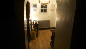 Un pasillo abovedado que conduce a una habitación con un radiador, una ventana y una pequeña mesa con lámpara.