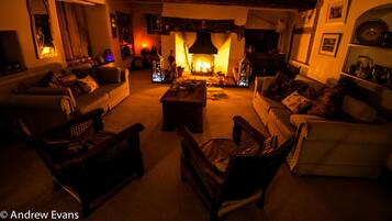A cozy living room with a fireplace, sofas, and armchairs arranged around a central coffee table.