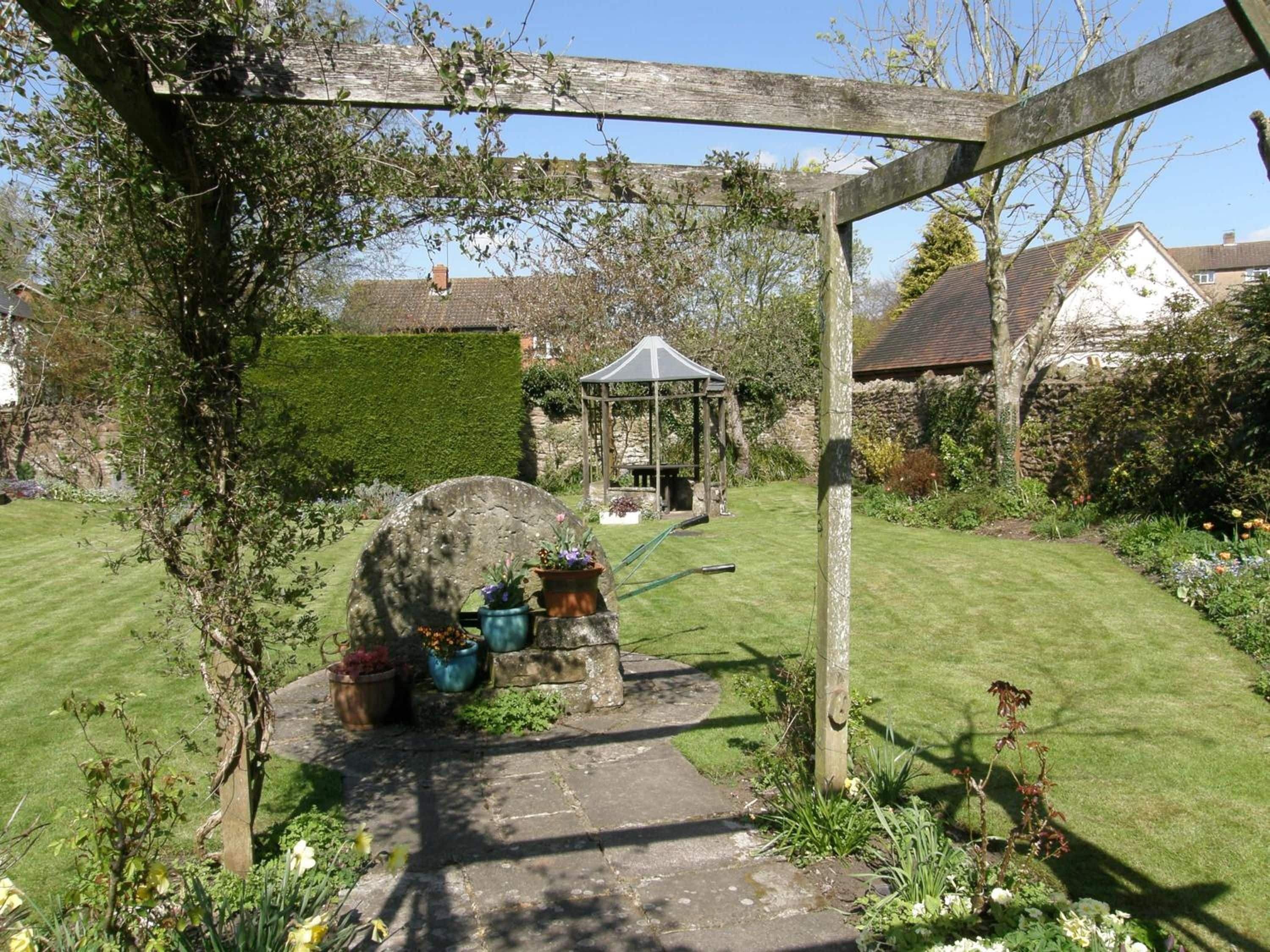 A garden with a gazebo, stone pathway, and potted plants.