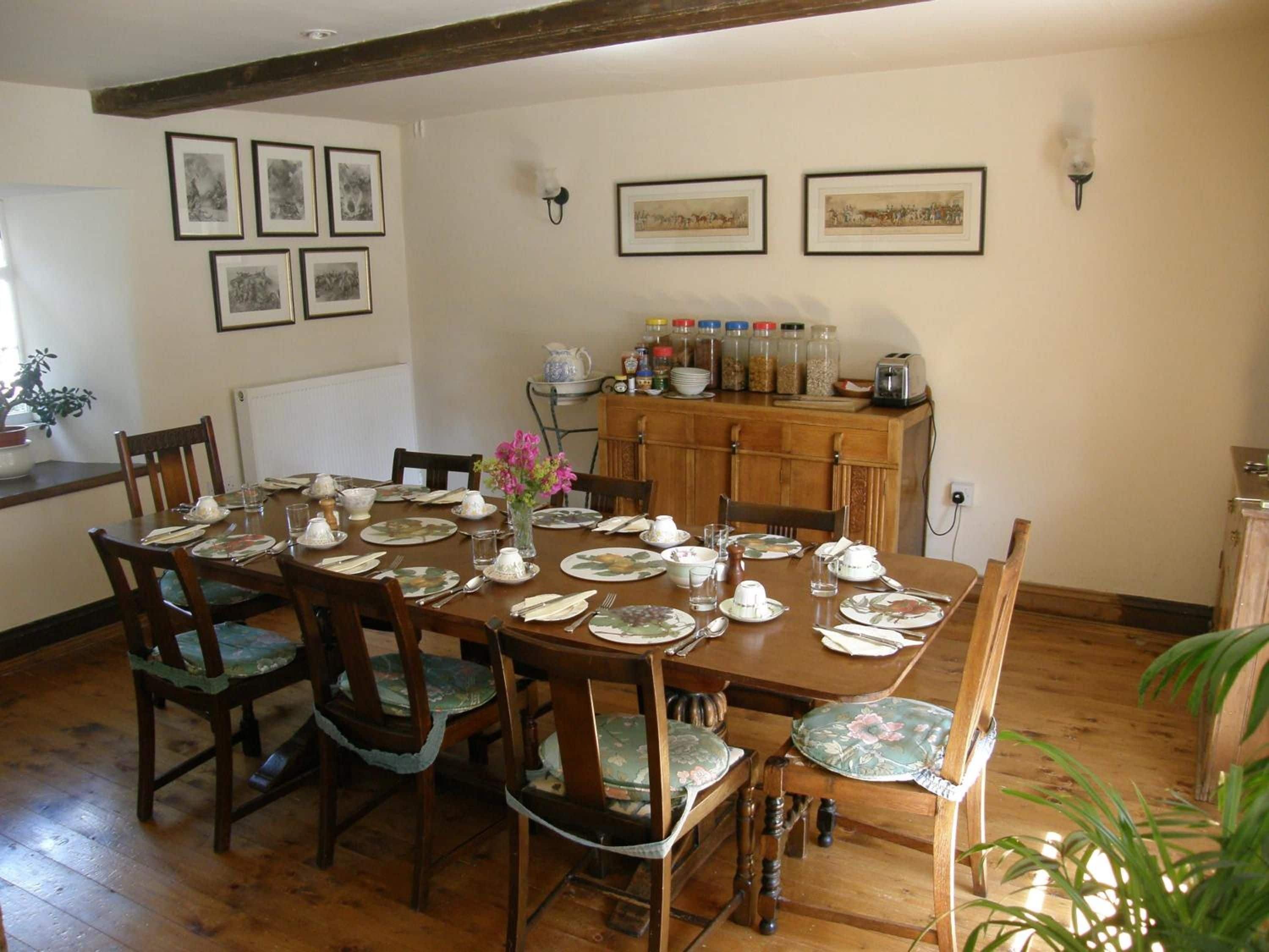 A dining room with a wooden table set for four, surrounded by chairs with floral upholstery.