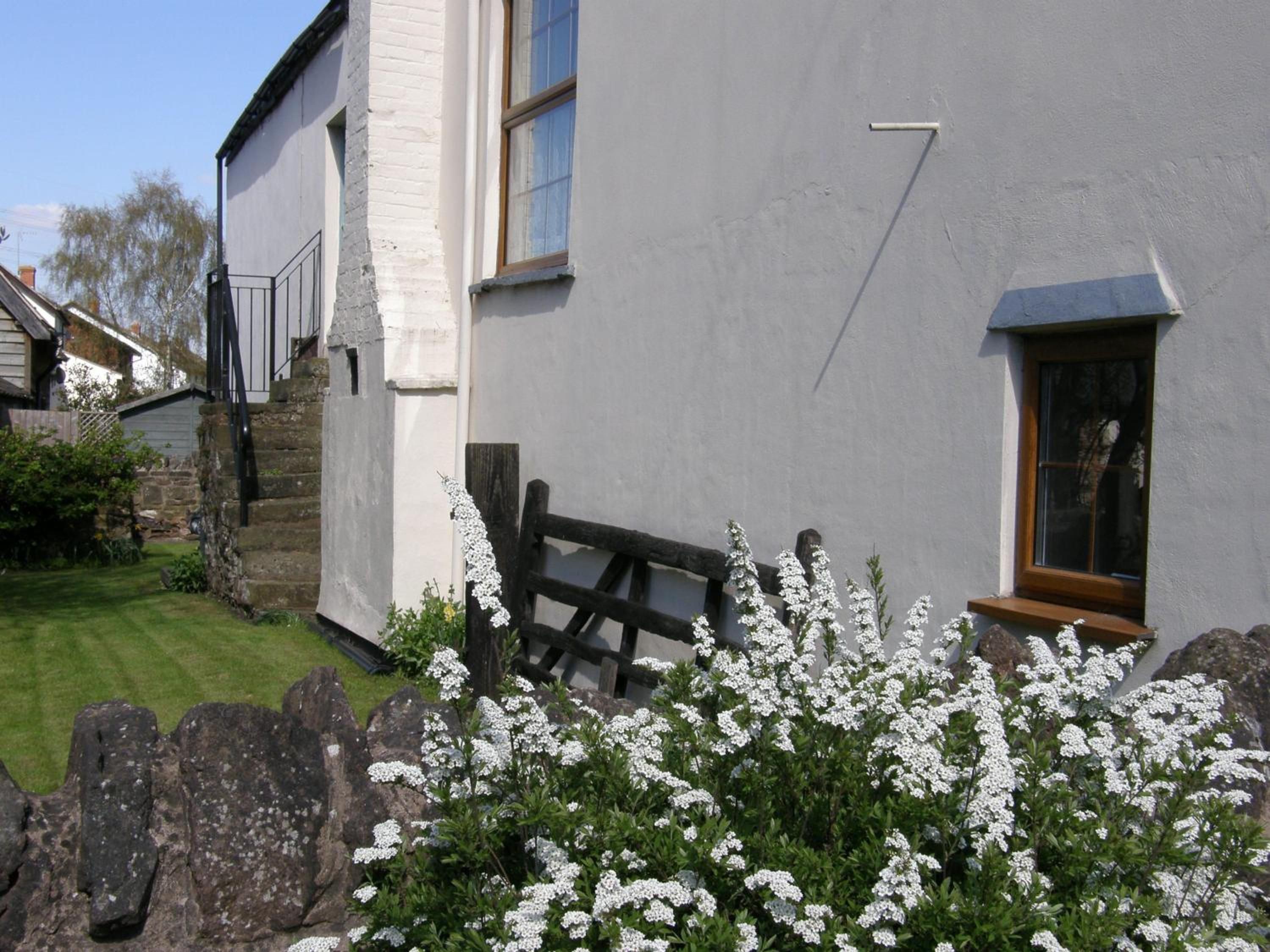 A house with a white exterior, a wooden fence, and a garden with white flowering plants.
