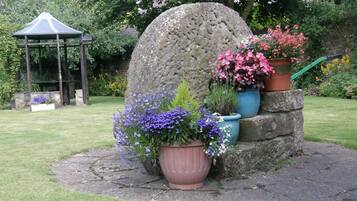 Un jardin agrémenté d’une structure en pierre, de plantes en pot et d’un belvédère.