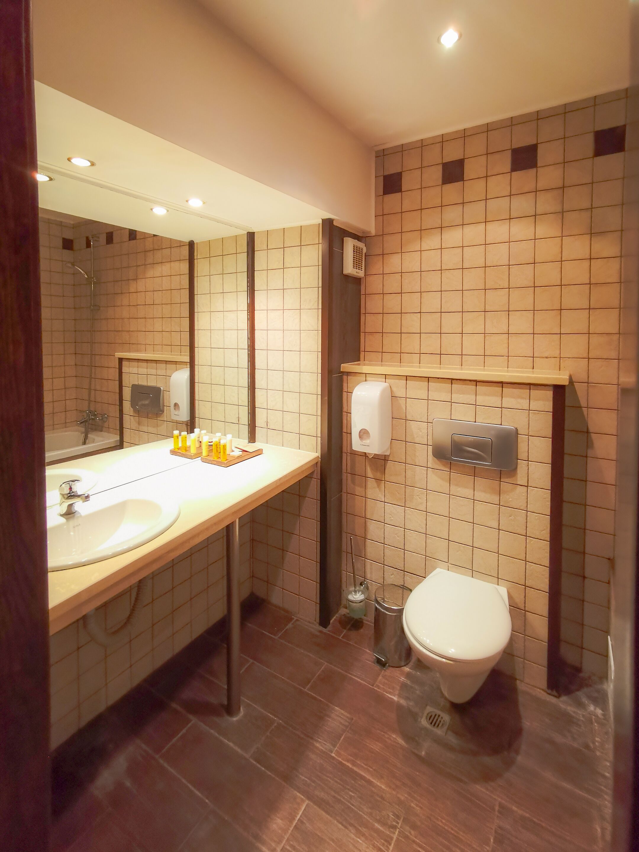 A modern bathroom with a sink, mirror, toilet, and hand dryer.