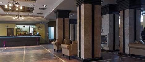 A lobby with a reception desk, seating area, and a fireplace.