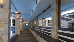 A corridor with stone pillars, a wooden floor, and a view of a pool area. - Trinity Residence Bansko (Bansko)