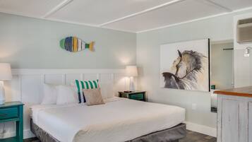 A bedroom with a large bed, two bedside tables, a wall-mounted fish decoration, and a horse painting.