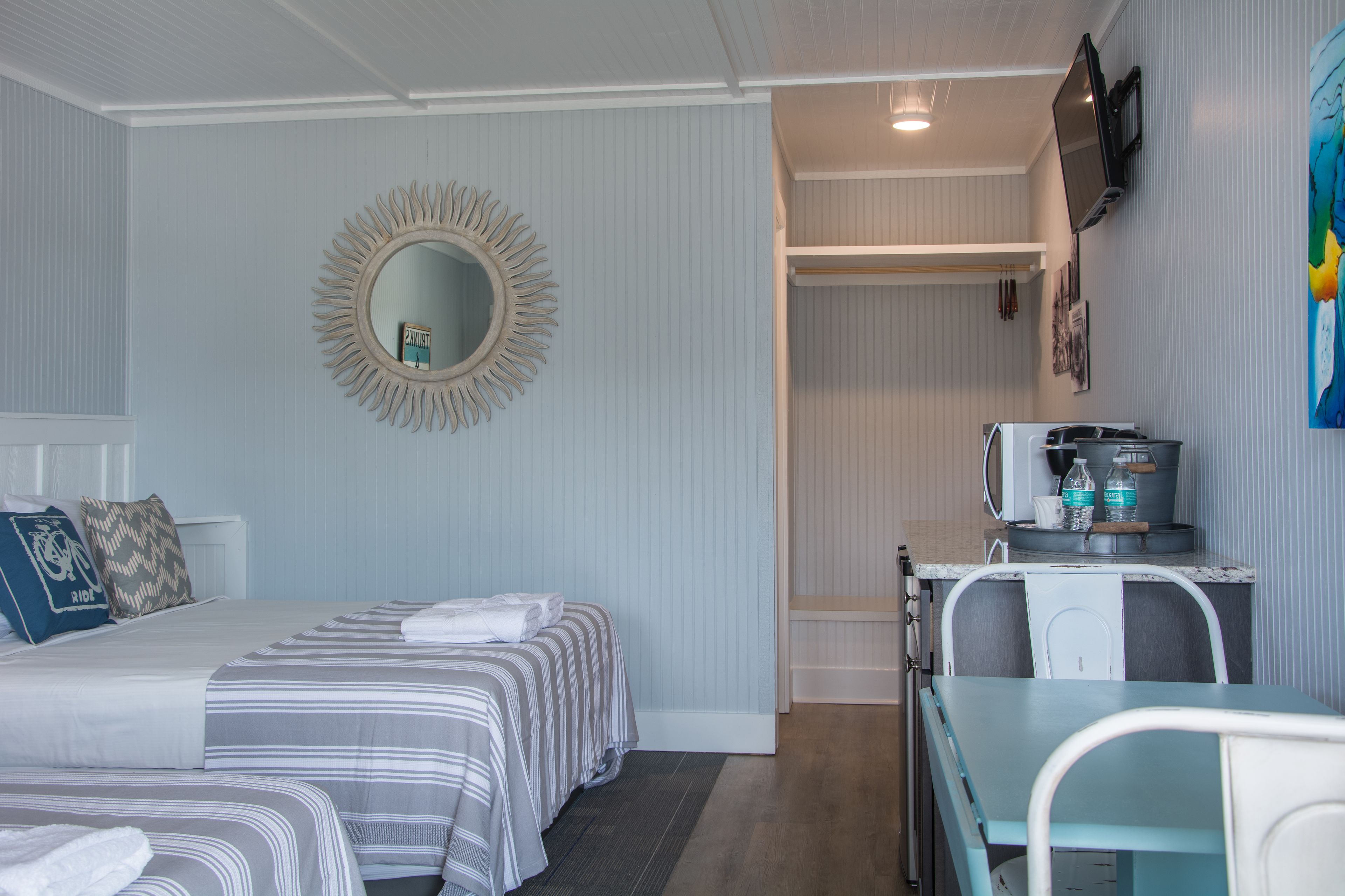 Une chambre d’hôtel avec deux lits, une petite kitchenette, une télévision et un miroir.