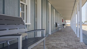 A covered outdoor area with a bench and a row of windows. - Tar Heel Motel (Nags Head)