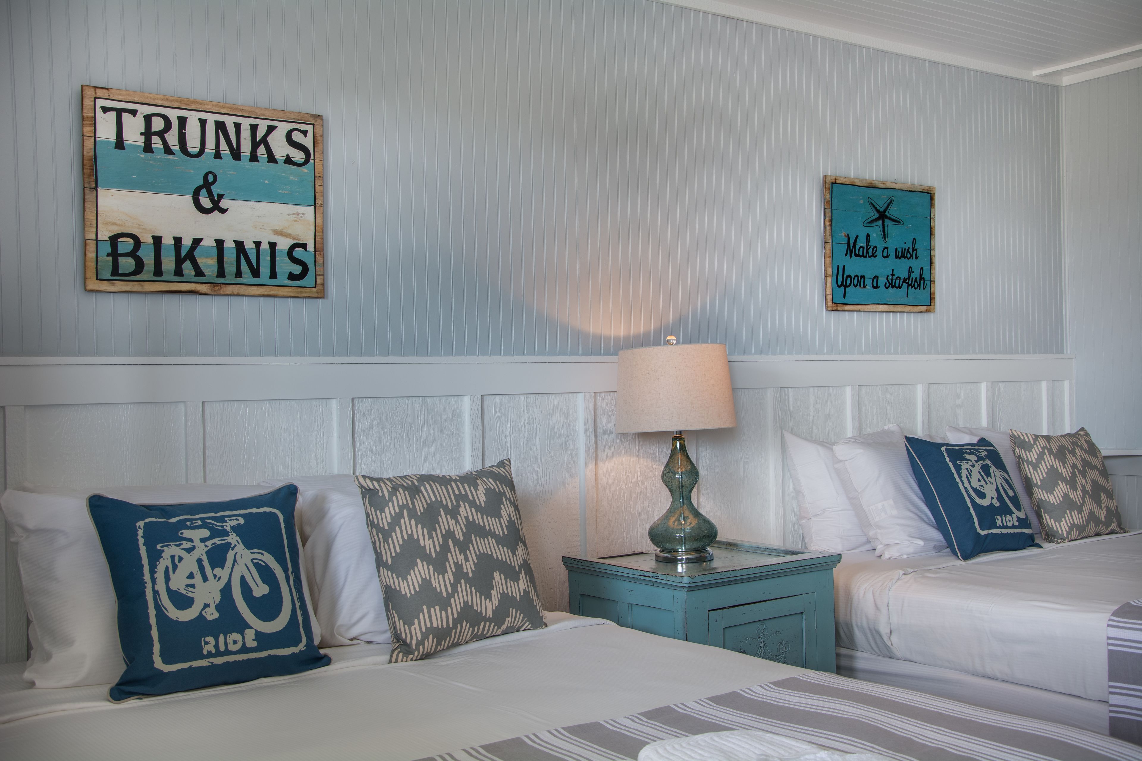Un dormitorio con dos camas, una mesita de noche y decoración en la pared.