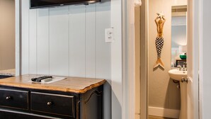 A bathroom with a wooden vanity, a mounted television, and a decorative fish sculpture. - Tar Heel Motel (Nags Head)