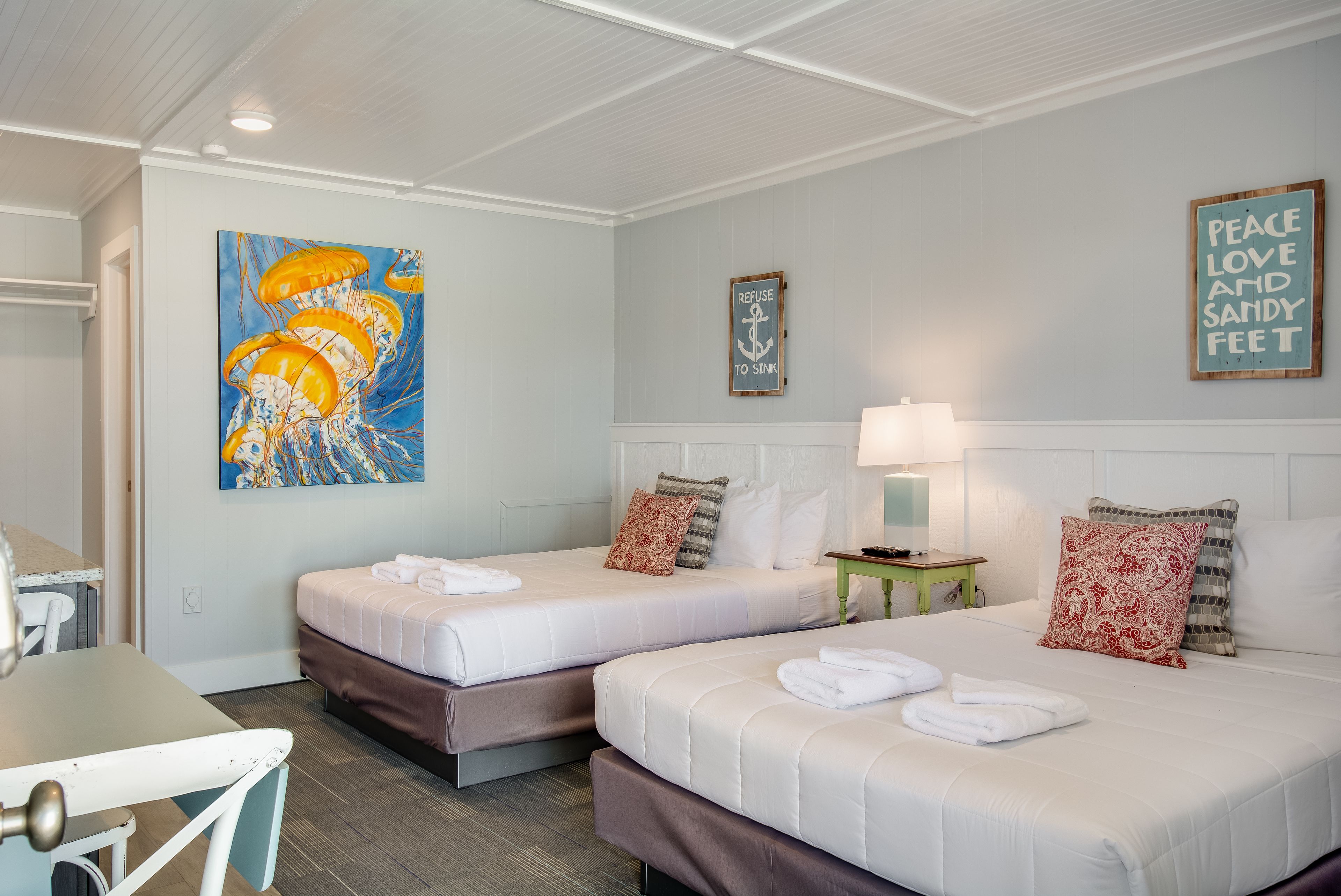 Une chambre d’hôtel avec deux lits, un bureau et un tableau.