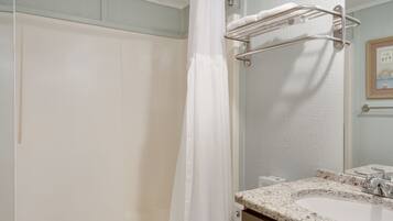 Un baño con ducha, un lavabo con encimera de mármol y un perchero para toallas.