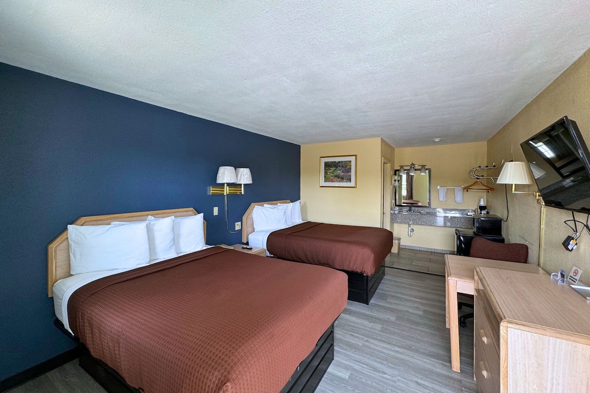 Une chambre d’hôtel avec deux lits, un bureau, une télévision et une kitchenette.
